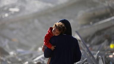 Eine palästinensische Mutter mit ihrem Kind geht während eines Waffenstillstands zwischen Israel und der Hamas in Gaza-Stadt am 11. 10. 2025 durch die Trümmer zerstörter Gebäude. 
