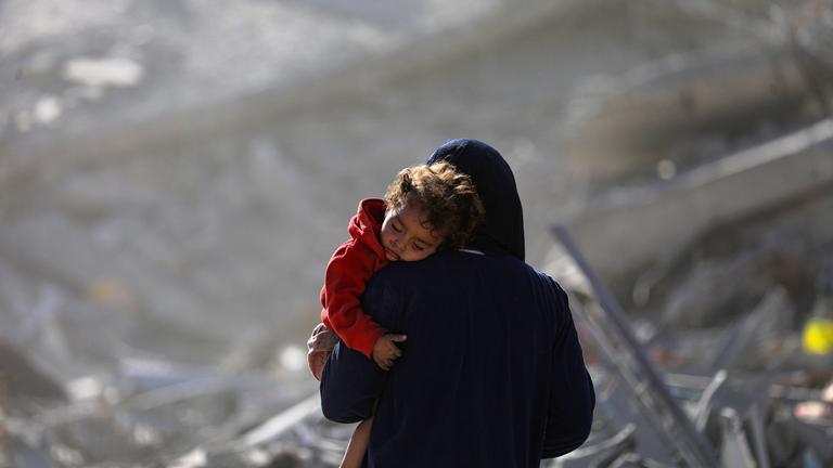 Eine palästinensische Mutter mit ihrem Kind geht während eines Waffenstillstands zwischen Israel und der Hamas in Gaza-Stadt am 11. 10. 2025 durch die Trümmer zerstörter Gebäude. 