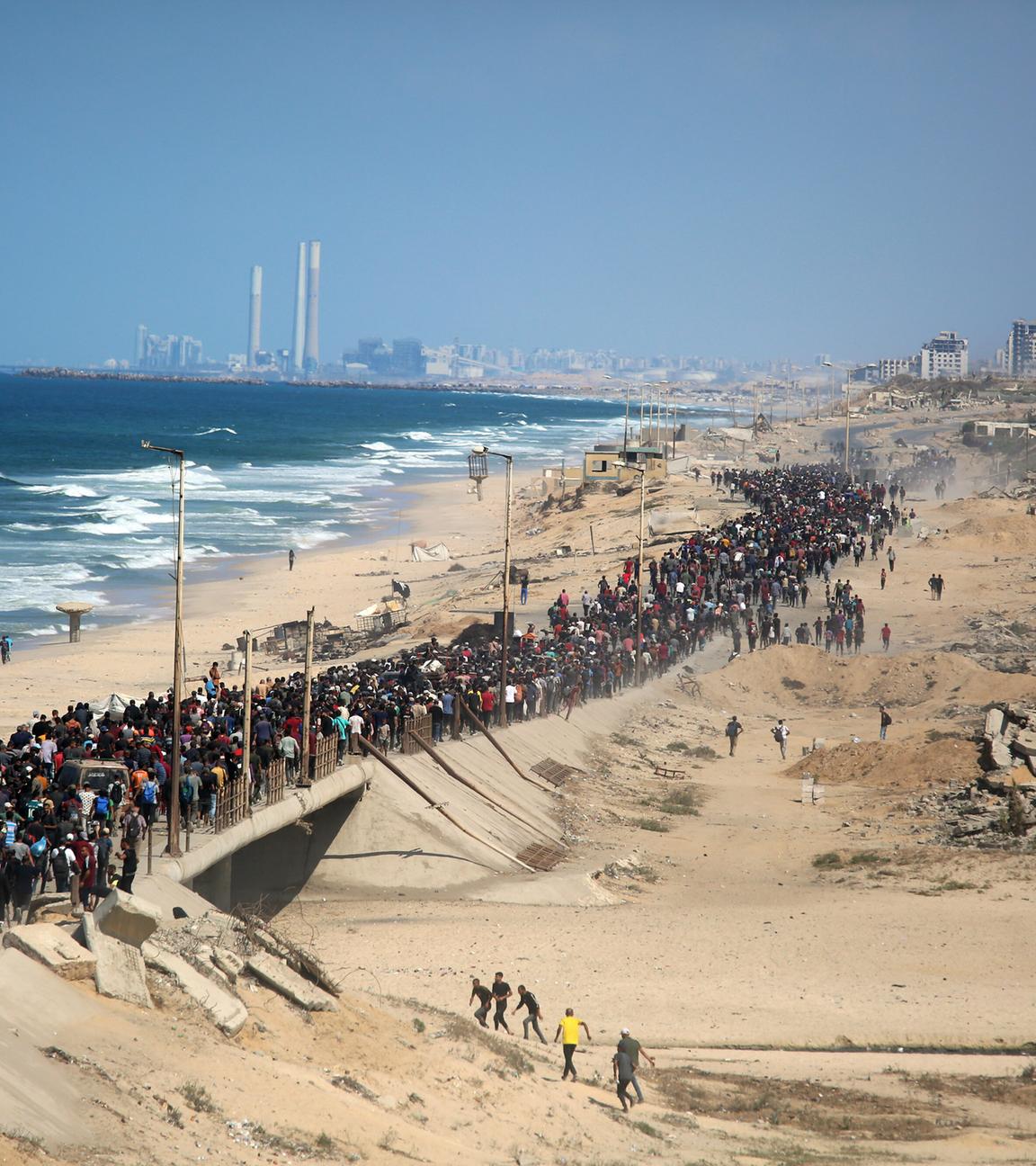 Thousands of displaced Palestinians walk along the Rashid coastal road toward Gaza City following the implementation of the ceasefire, in the central Gaza Strip