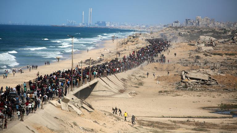 Thousands of displaced Palestinians walk along the Rashid coastal road toward Gaza City following the implementation of the ceasefire, in the central Gaza Strip