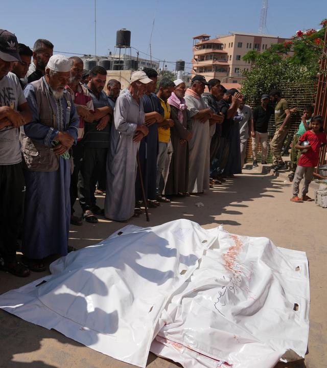 Palästinenser beten vor den Leichen von Ahmed Abu Hilal und Ibrahim Al-Najjar, die auf dem Weg zu einem Hilfszentrum in Gaza getötet wurden.