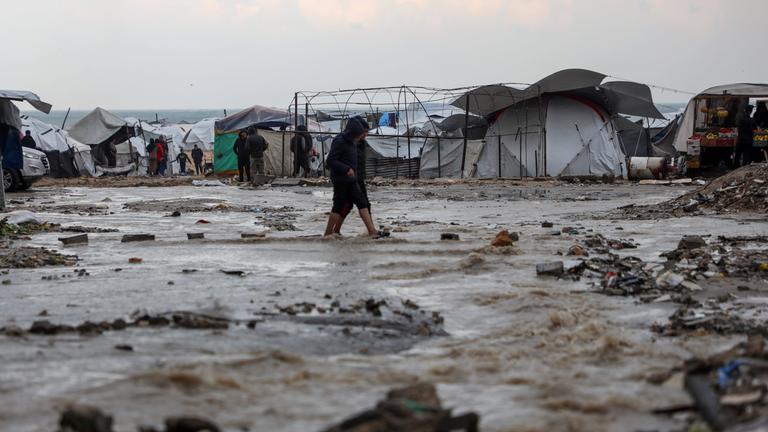 Palästinenser gehen nach Regenfällen in Gaza-Stadt am 12.12.2025 durch eine überflutete Straße.