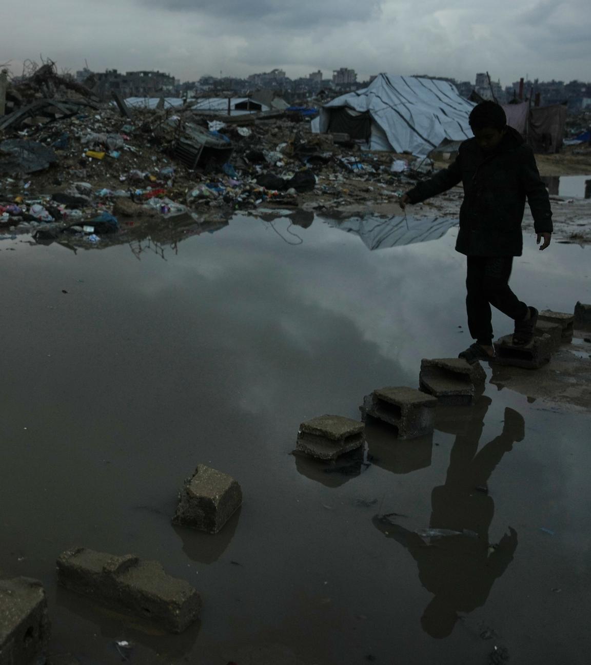 Ein Palästinenser läuft durch eine Gegend mit zerstörten Gebäuden und Unwetterfolgen in Gaza.