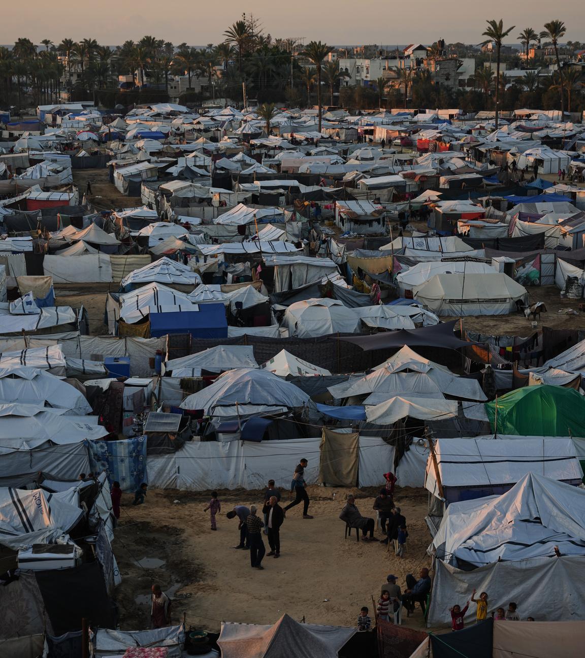 Displaced Palestinians gather outside a tent at a temporary camp in Deir al-Balah.