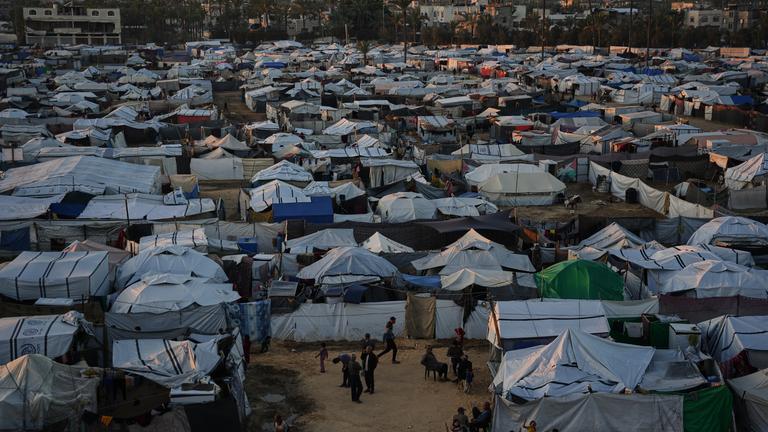 Displaced Palestinians gather outside a tent at a temporary camp in Deir al-Balah.