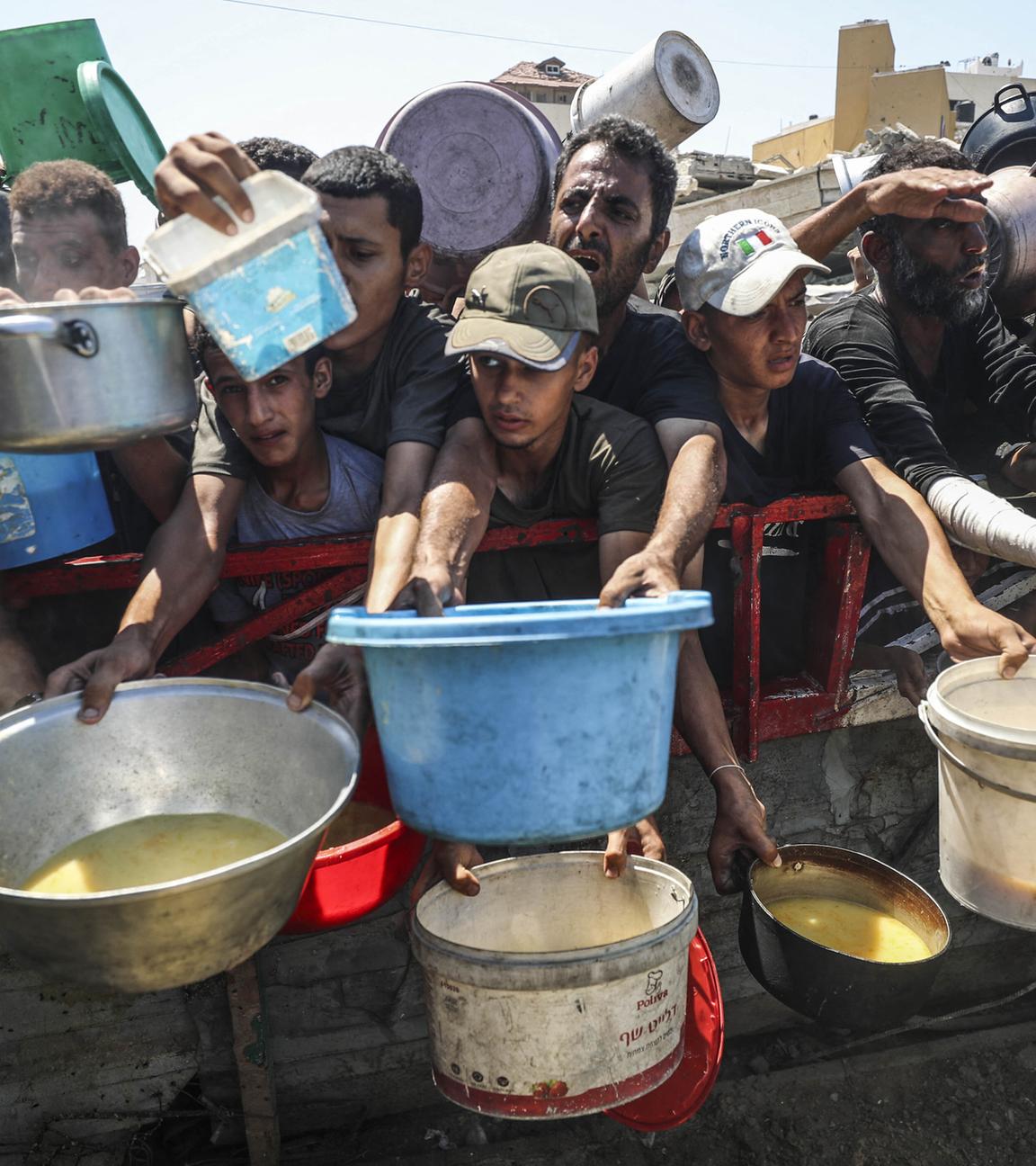Palästinenser, die Hunger leiden, warten auf eine warme Mahlzeit, an einer Verteilstelle der Welthungerhilfe in Gaza