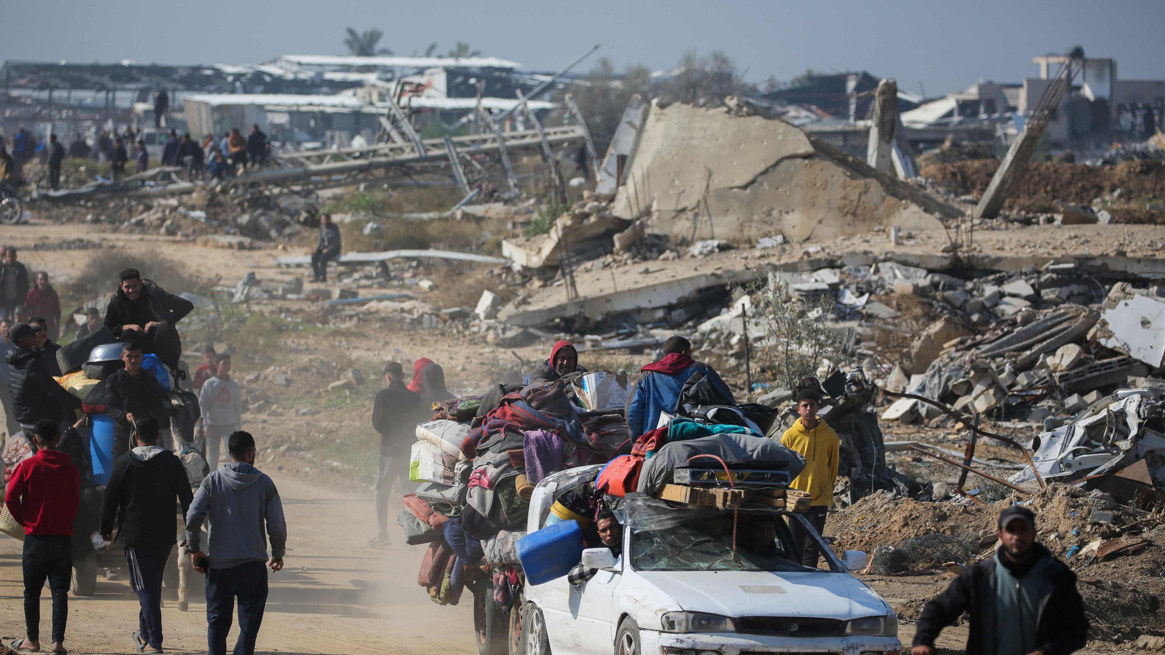 Displaced Palestinians walk towards Gaza City as they cross the Netzarim corridor from the southern Gaza Strip on January 27
