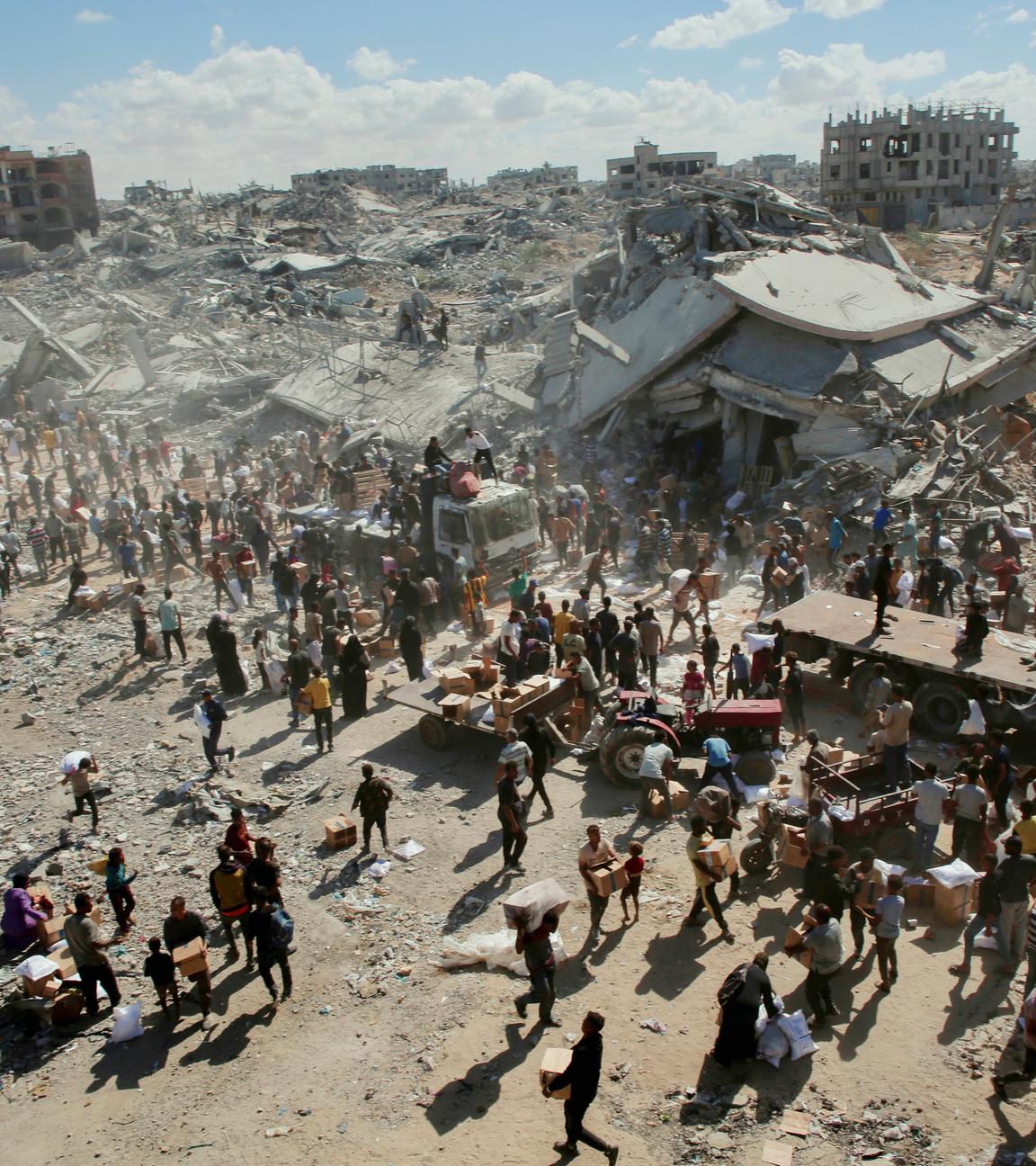Menschen gehen am 12.10.2025 durch eine stark beschädigte Straße in Khan Yunis im südlichen Gazastreifen. 