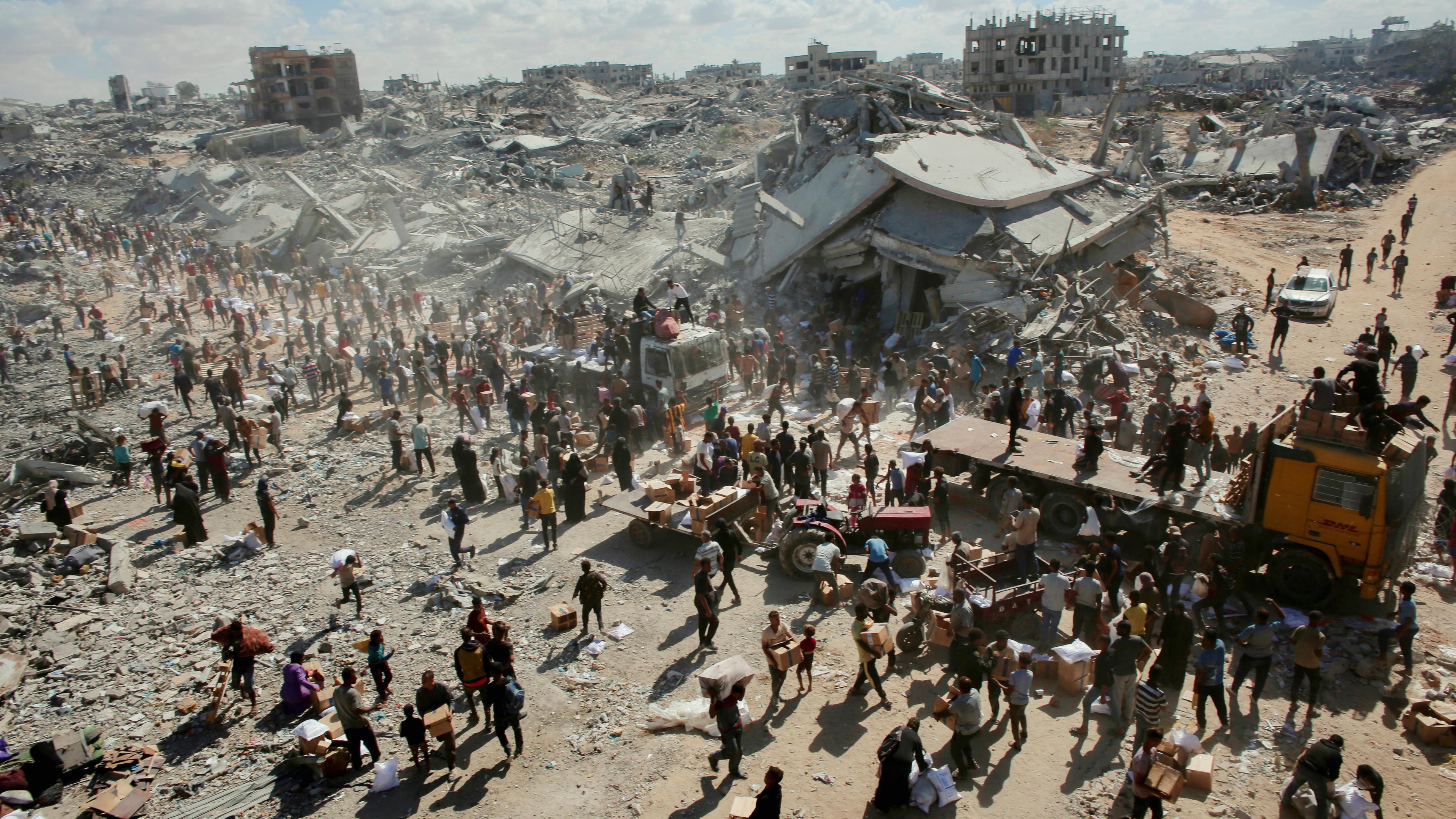 Menschen gehen am 12.10.2025 durch eine stark beschädigte Straße in Khan Yunis im südlichen Gazastreifen. 