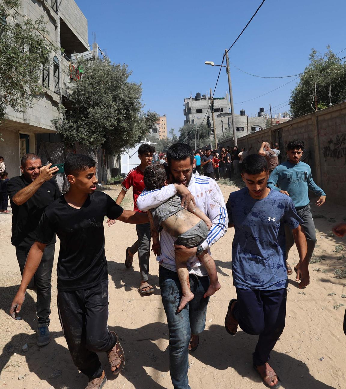 Palästinenser eilen zu einem verletzten Kind im Lager Al-Bureij im zentralen Gazastreifen, nachdem das Gebiet Ziel eines israelischen Angriffs war.