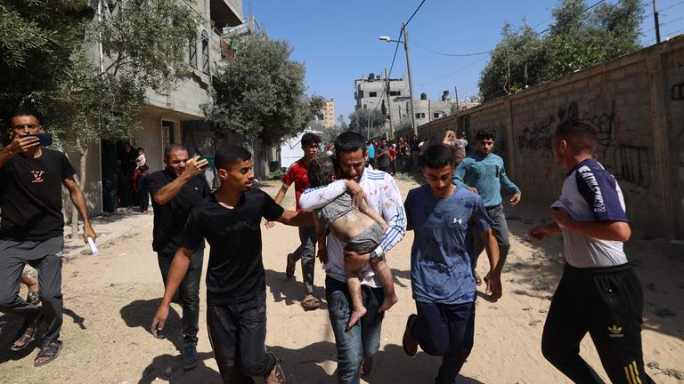 Palästinenser eilen zu einem verletzten Kind im Lager Al-Bureij im zentralen Gazastreifen, nachdem das Gebiet Ziel eines israelischen Angriffs war.