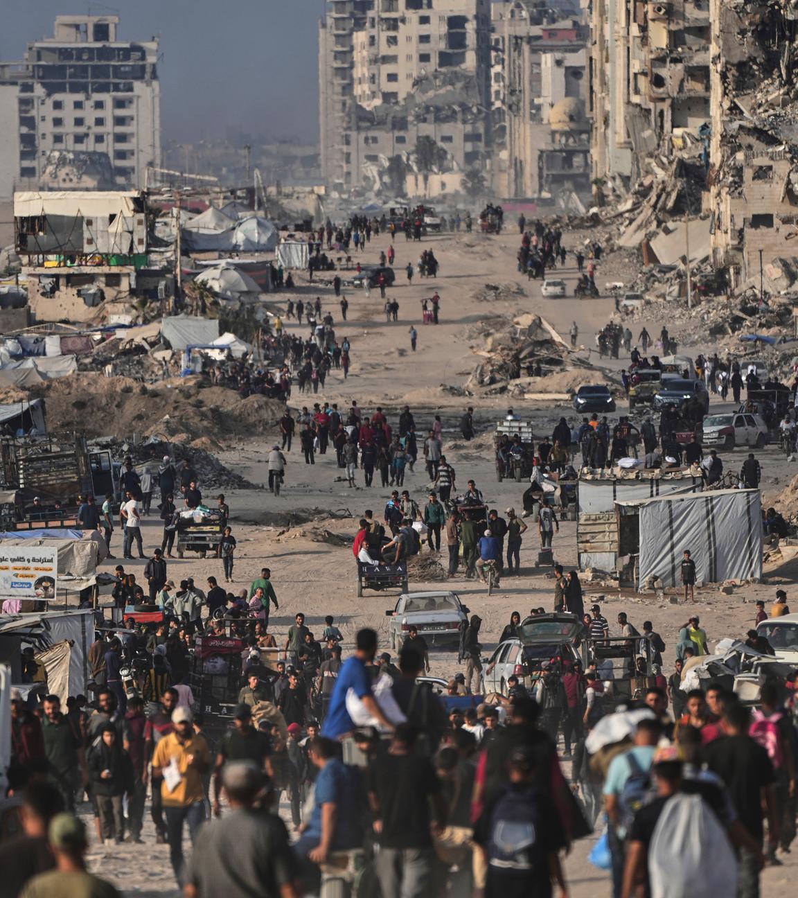 Palästinenser gehen zwischen zerstörten Gebäuden in Gaza-Stadt.