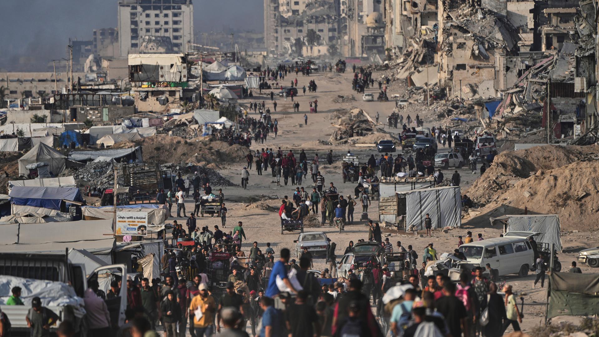 Palästinenser gehen zwischen zerstörten Gebäuden in Gaza-Stadt.