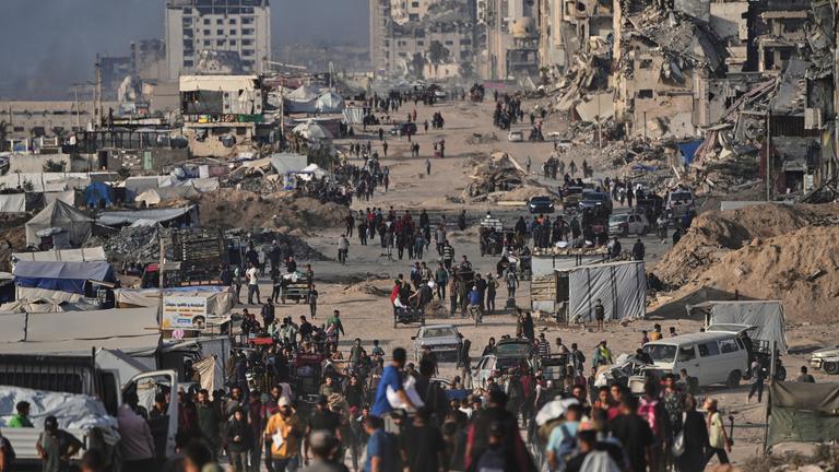 Palästinenser gehen zwischen zerstörten Gebäuden in Gaza-Stadt.