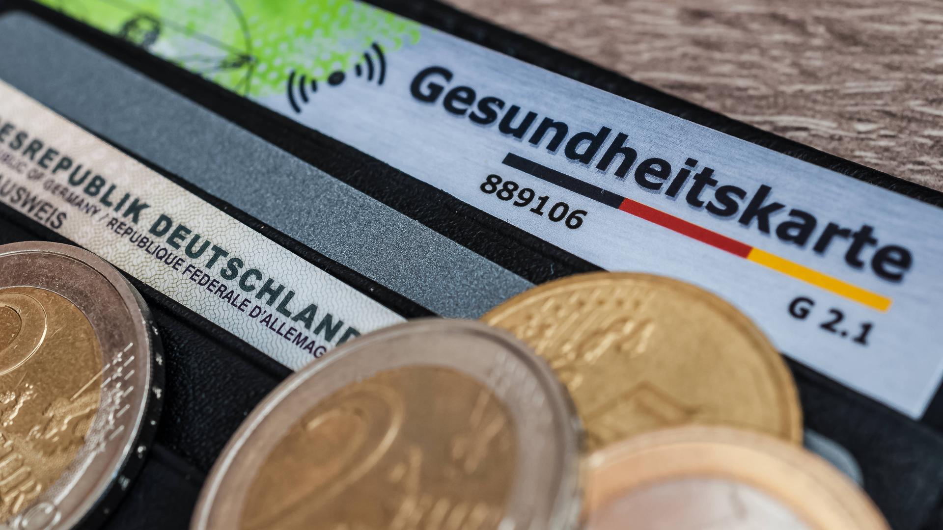 Eine Krankenversicherungskarte mit Kleingeld auf einem Geldbeutel.