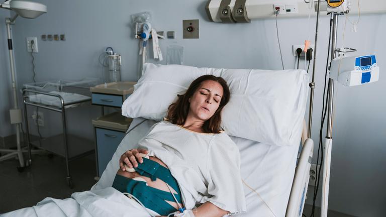 Schwangere Frau mit Schmerzen im Krankenhausbett