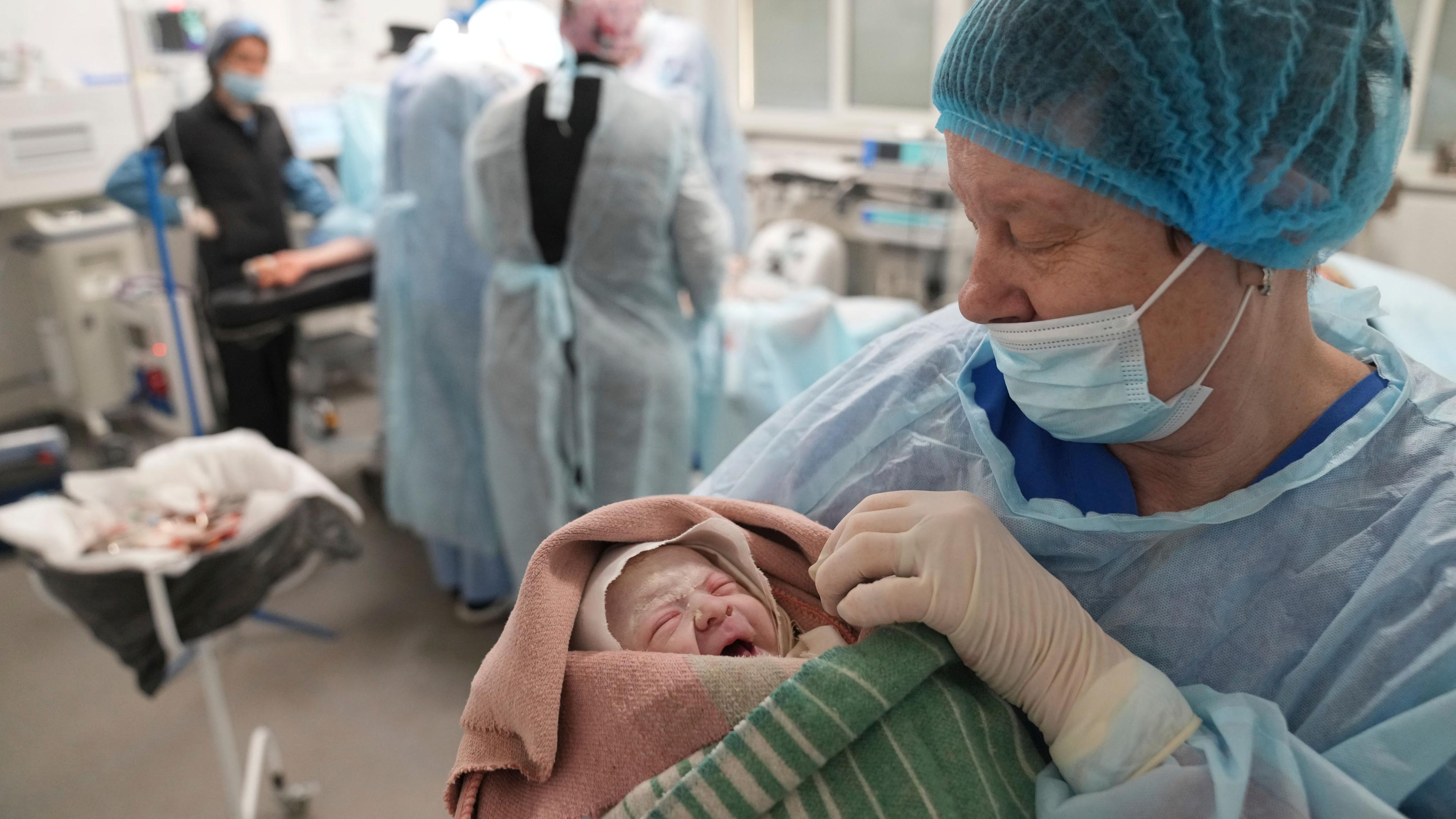 Eine Krankenschwester hält ein Neugeborenes in einem Krankenhaus in Mariupol in den Armen. 