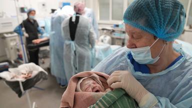 Eine Krankenschwester hält ein Neugeborenes in einem Krankenhaus in Mariupol in den Armen. 