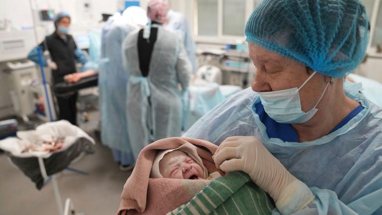 Eine Krankenschwester hält ein Neugeborenes in einem Krankenhaus in Mariupol in den Armen. 