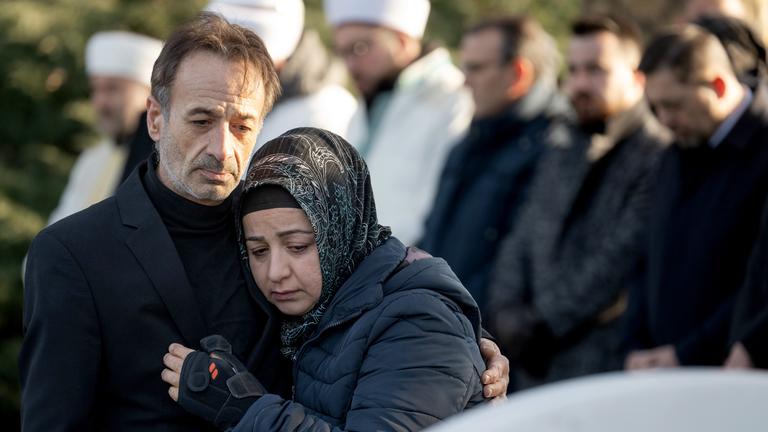 ngehörige stehen während der Gedenkfeier für die Opfer des Anschlags vor einem Grabstein, aufgenommen am 19.02.2025 in Hanau