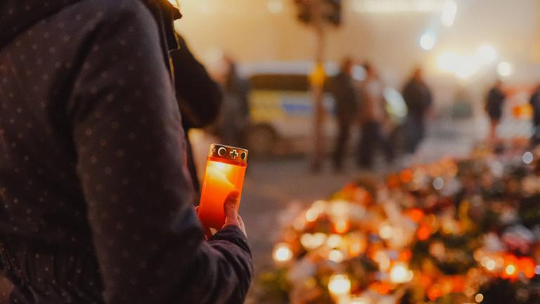 Archiv: Auch am 2. Weihnachtsfeiertag kommen weiterhin viele Menschen zur Johanniskirche um den Opfern zu gedenken, Das Blumenmeer wächst immer weiter, eine angeündete Kerze, Frau stellt eine Kerze zum Trauern auf, Anschlag auf den Magdeburger Weihnachtsmarkt, Sachsen-Anhalt, 20.12.2024