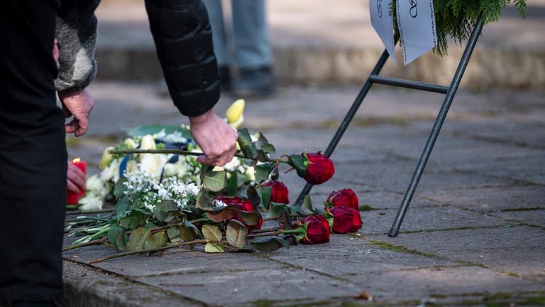 Personen legen Blumen am Trauerkranz im Park Schöntal zum Gedenken an die tödliche Messerattacke in Aschaffenburg ab.