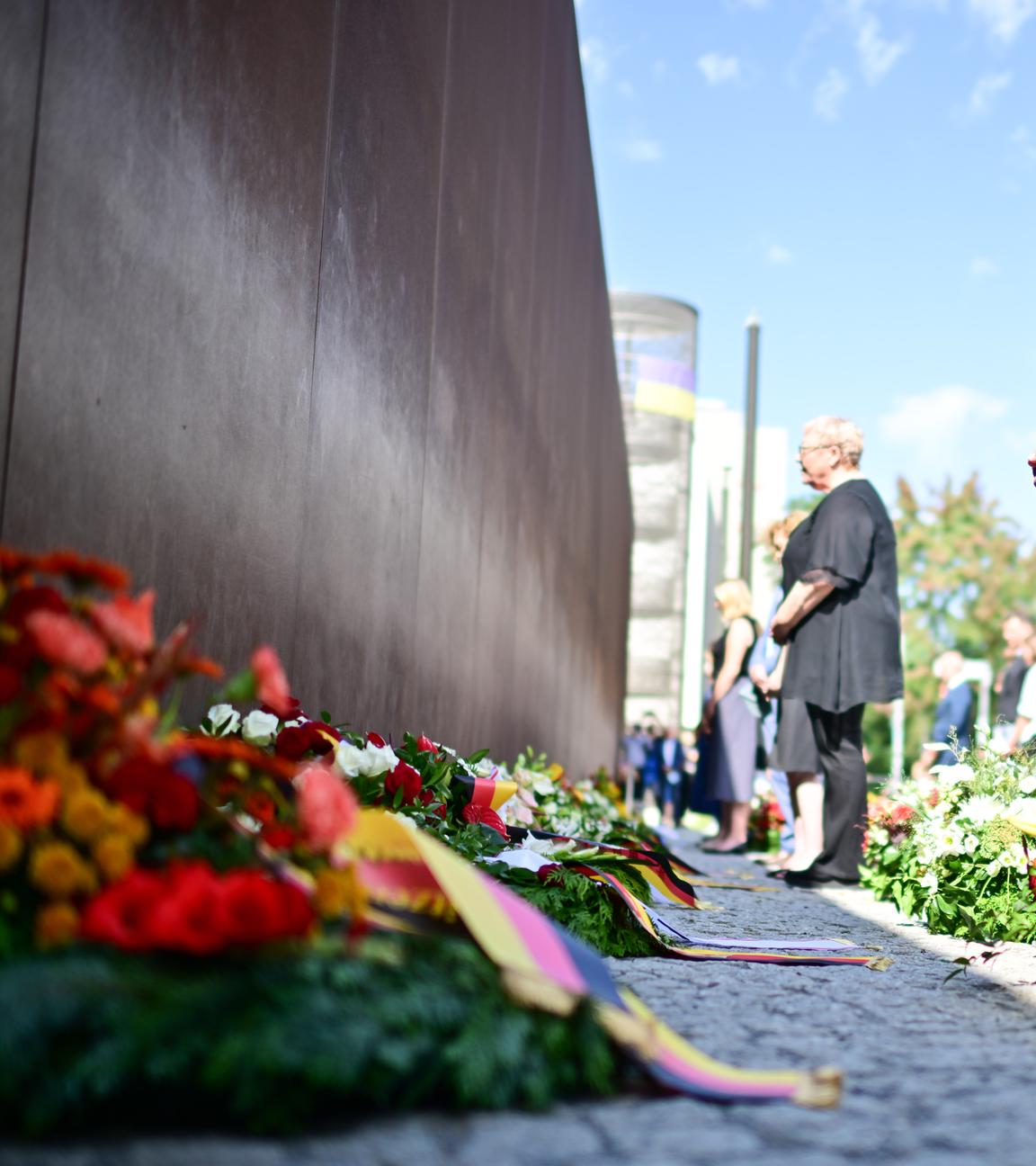Kai Wegner (CDU, M), Regierender Bürgermeister von Berlin, nimmt während einer Kranzniederlegung an der Mauergedenkstätte Ecke Acker-/Bernauer Straße mit weiteren Teilnehmern an einer Gedenkminute teil. 