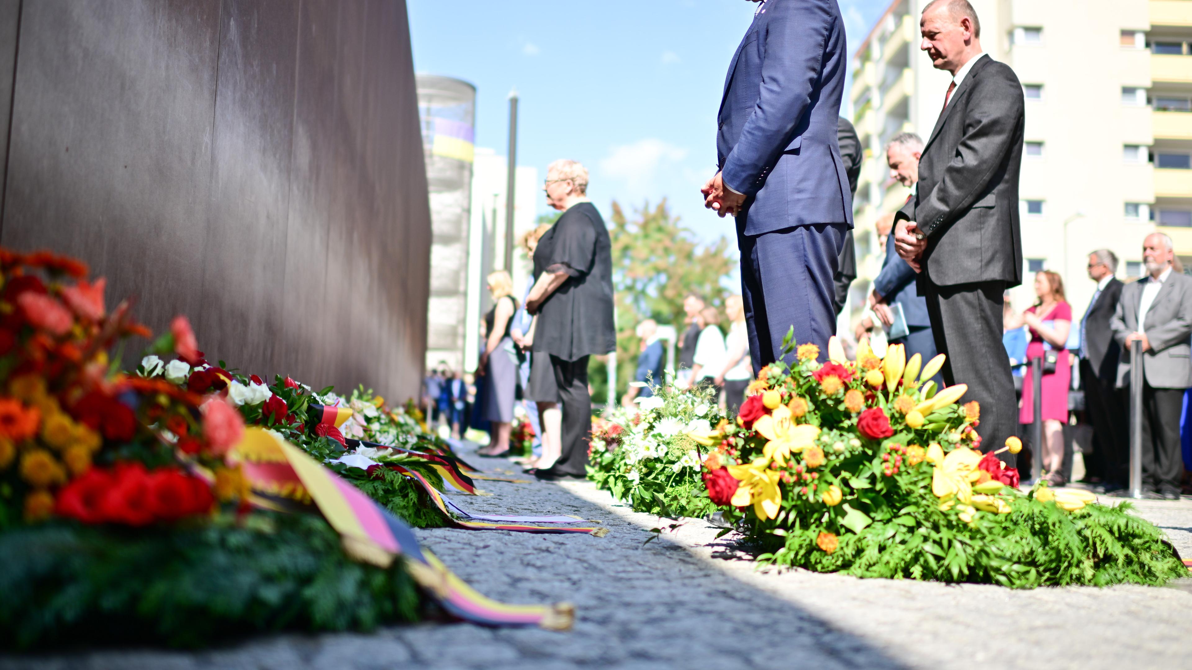 Kai Wegner (CDU, M), Regierender Bürgermeister von Berlin, nimmt während einer Kranzniederlegung an der Mauergedenkstätte Ecke Acker-/Bernauer Straße mit weiteren Teilnehmern an einer Gedenkminute teil. 