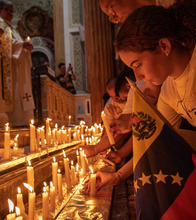 Ein Mädchen zündet eine Kerze während einer Messe an. Vor ihr stehen viele weitere Kerzen zu Gedenken an die Erdbebenopfer in Venezuela.