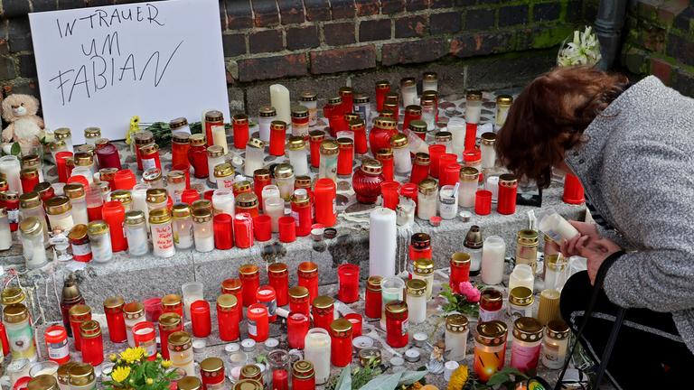 An der Marienkirche in Güstrow stehen Grablichter, Blumen und Plüschtiere im Gedenken an den vermissten achtjährigen Fabian, auf einem Schild steht "In Trauer um Fabian". 