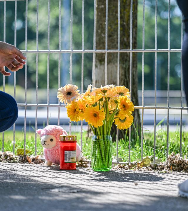 Eine Frau legt Blumen nieder, nachdem ein lebloses Kind in einem Auto gefunden wurde