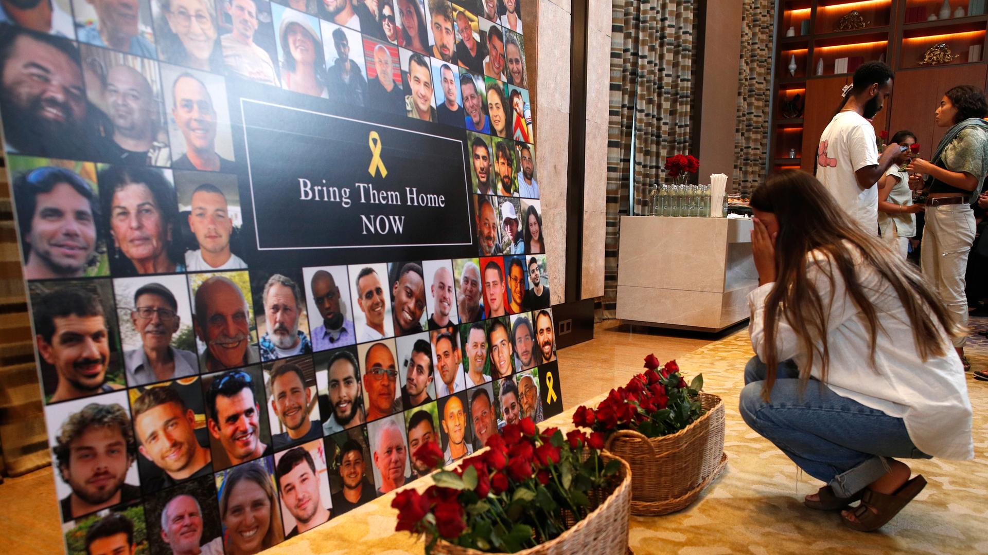 Eine Frau kniet nieder, als sie während einer Gedenkzeremonie anlässlich des ersten Jahrestages des Hamas-Angriffs auf Israel in Bangkok, Blumen zum Gedenken an Geiseln und Opfer niederlegt.