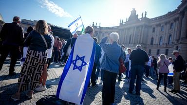 Berlin: Teilnehmer zeigen die Fahne Israels bei einer Gedenkveranstaltung zum Jahrestag des Terrorangriffs der Hamas auf Israel auf dem Bebelplatz