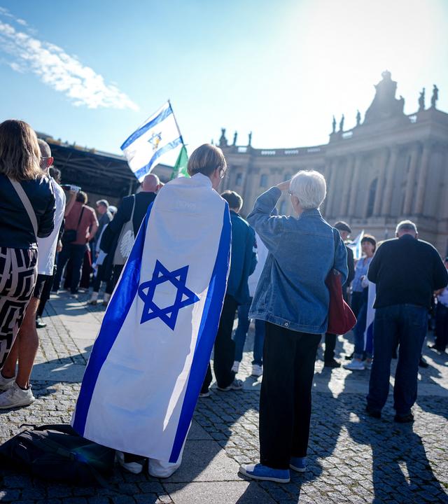 Berlin: Teilnehmer zeigen die Fahne Israels bei einer Gedenkveranstaltung zum Jahrestag des Terrorangriffs der Hamas auf Israel auf dem Bebelplatz