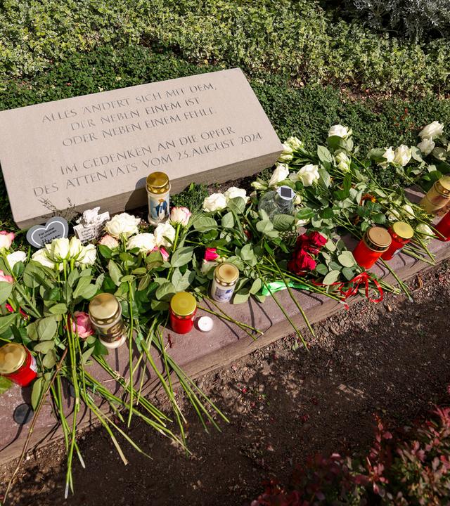 Nordrhein-Westfalen, Solingen: Weiße Rosen und Kerzen liegen am Gedenkstein für die Opfer des Terroranschlags von Solingen. Archivbild