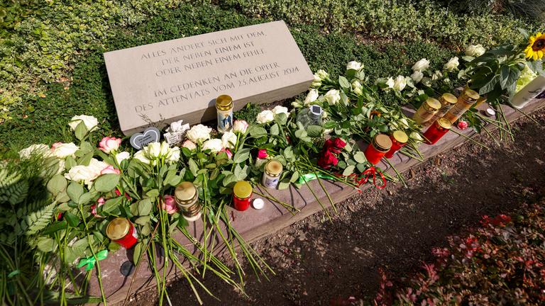 Nordrhein-Westfalen, Solingen: Weiße Rosen und Kerzen liegen am Gedenkstein für die Opfer des Terroranschlags von Solingen. Archivbild
