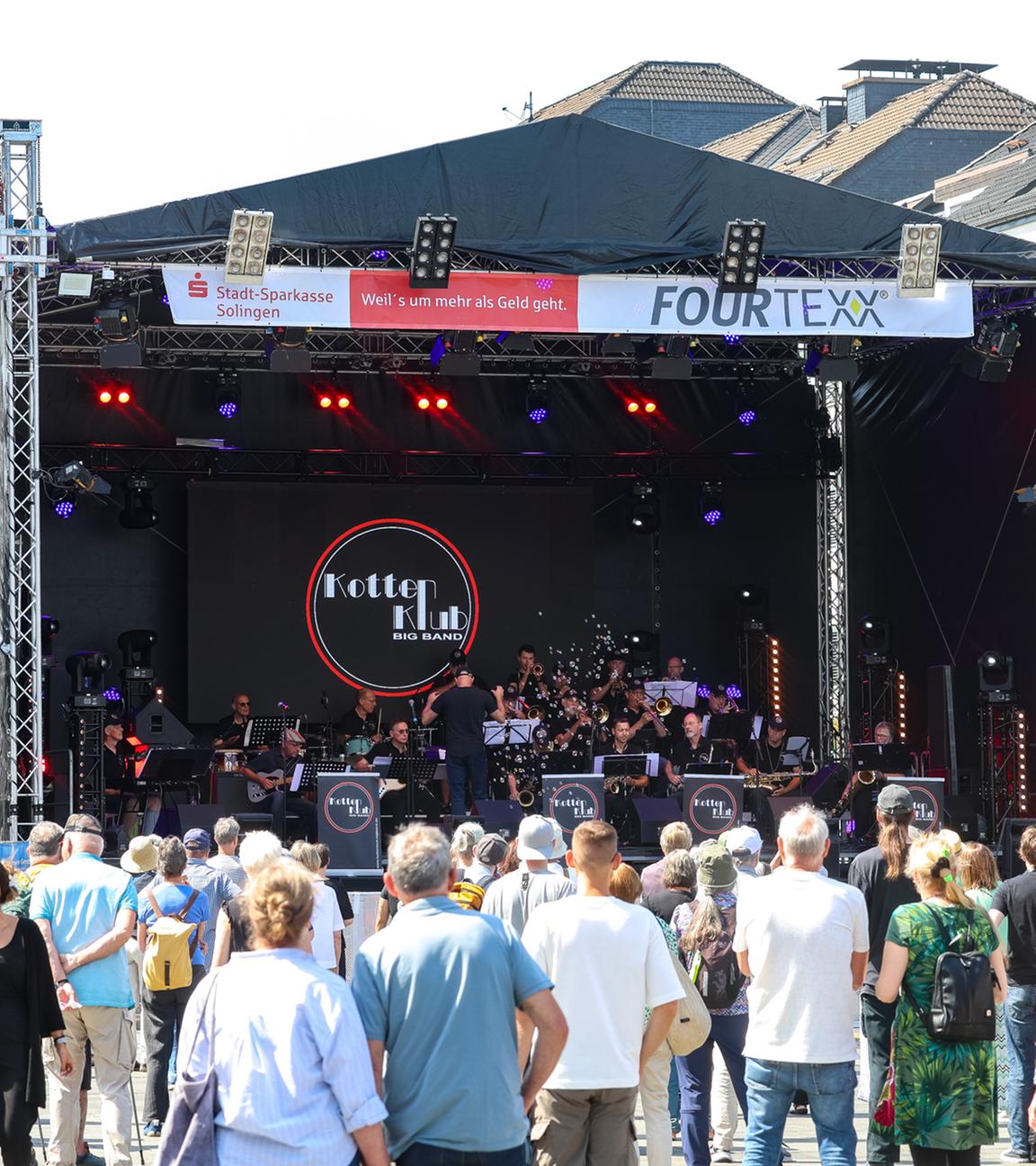 Nordrhein-Westfalen, Solingen: Besucher stehen auf dem Solinger Neumarkt während eines Gedenkkonzerts der Kotten Klub Bigband auftritt.