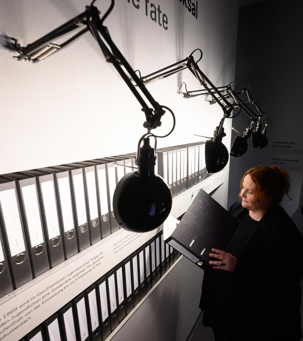 22.11.2024, Sachsen, Torgau: Manuela Rummel von der ·Gedenkstätte Geschlossener Jugendwerkhof Torgau· blättert in der neuen Ausstellung in einer Sonderakte, die für jeden Jugendlichen hier angelegt wurde.