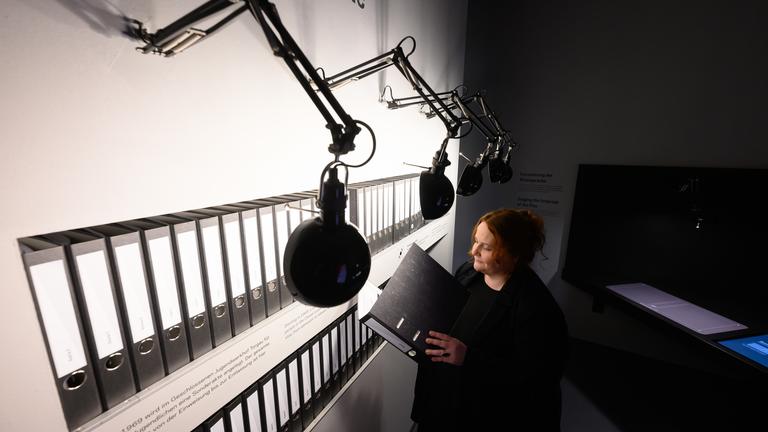 22.11.2024, Sachsen, Torgau: Manuela Rummel von der ·Gedenkstätte Geschlossener Jugendwerkhof Torgau· blättert in der neuen Ausstellung in einer Sonderakte, die für jeden Jugendlichen hier angelegt wurde.