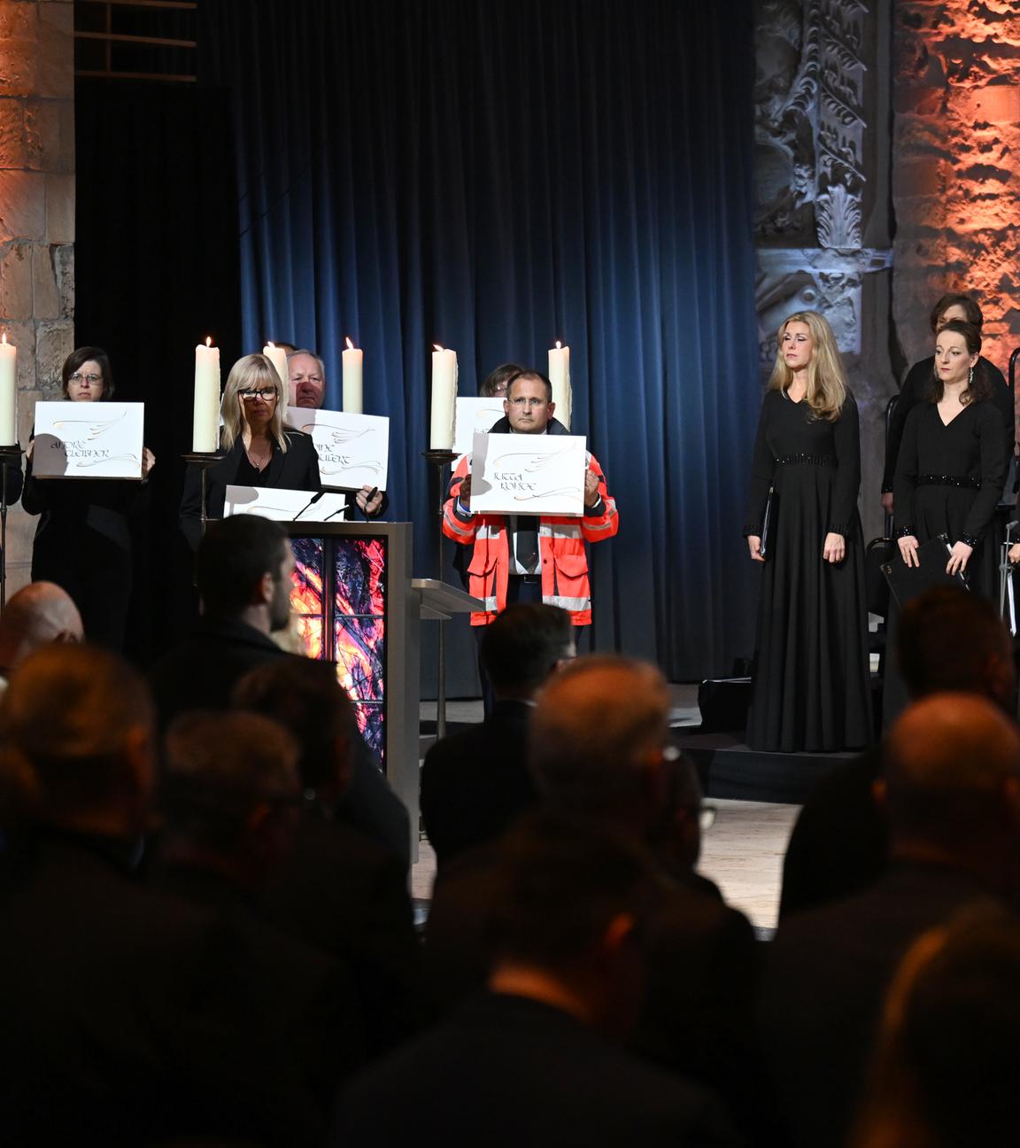 Die Gedenkveranstaltung für die Opfer des Anschlags auf dem Magdeburger Weihnachtsmarkt. Betroffene und Hilfskräfte alten Schilder mit den Namen der Opfer. 