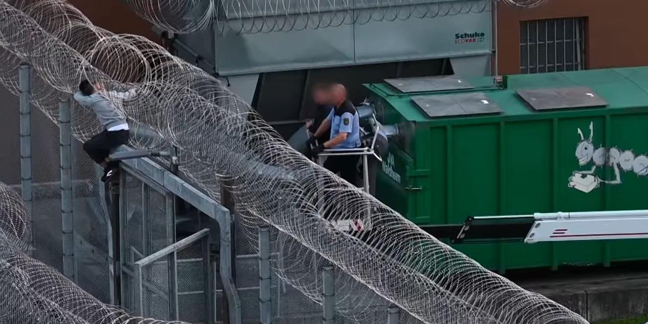 Bei dem Versuch über die letzte Mauer zu klettern, die den 28-Jährigen von seiner Freiheit trennt, bleibt der Insasse im Stacheldrahtzaun hängen.