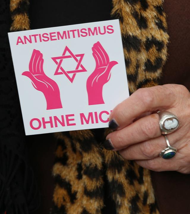 Detailaufnahme einer Teilnehmerin der Solidaritätsaktion Berlin trägt Davidstern mit einem Aufkleber Antisemitismus ohne mich und Davidstern.