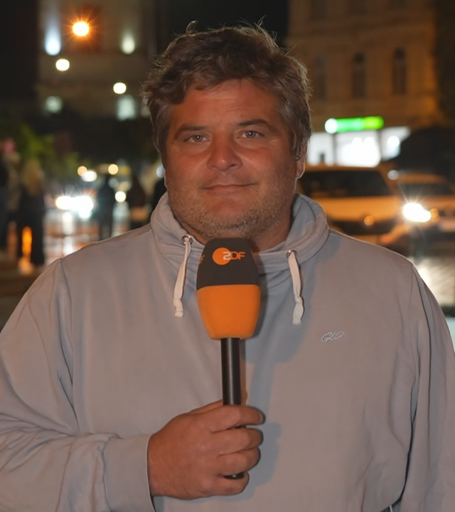 ZDF-Reporter Hassanzadeh vor einer befahrenen Straße nachts.