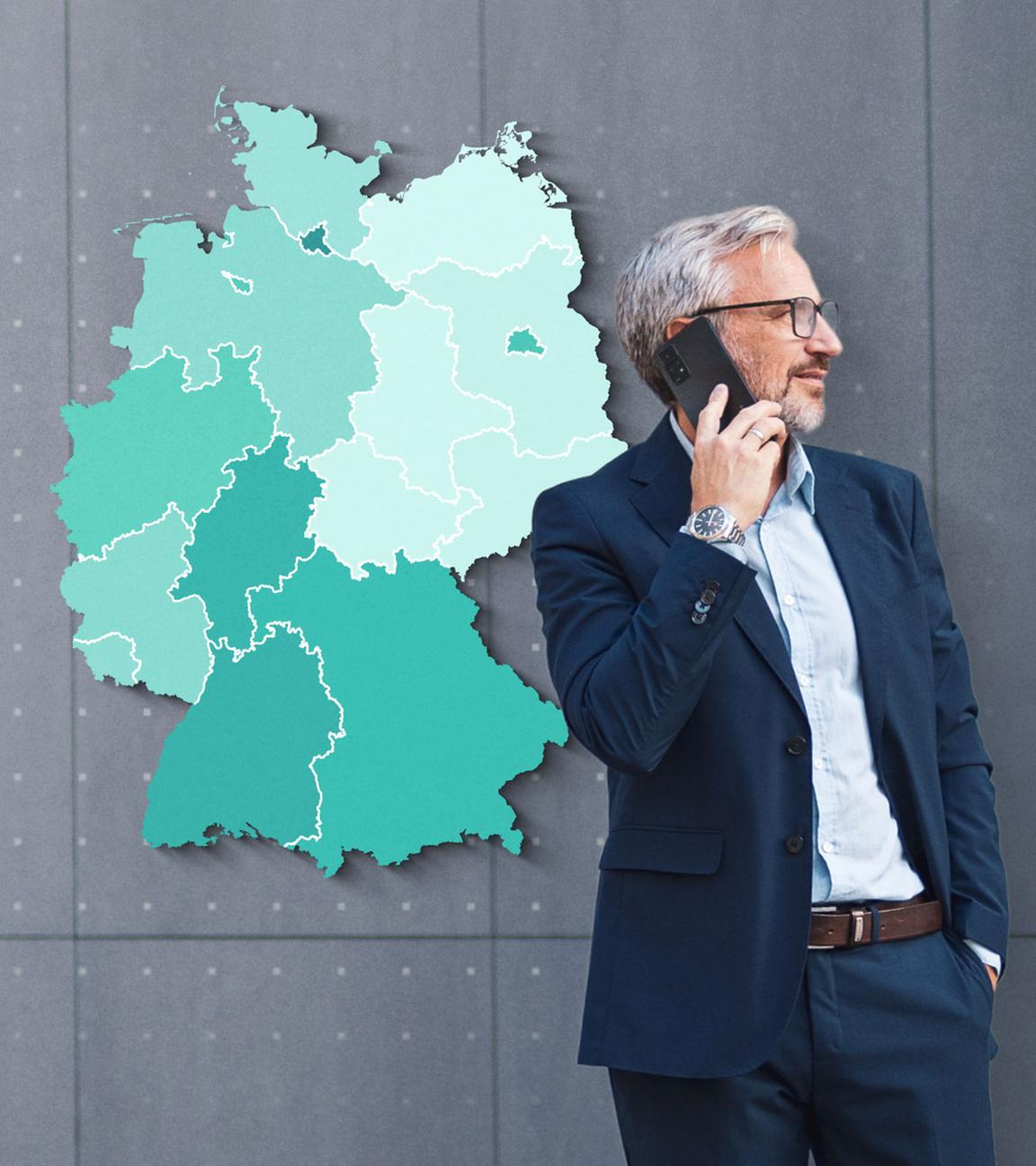 Ein Mann in einem blauen Anzug telefoniert über ein Smartphone. Im Hintergrund ist eine Grafik einer Deutschlandkarte mit in unterschiedlichen Grüntönen markierten Bundesländern zu sehen.