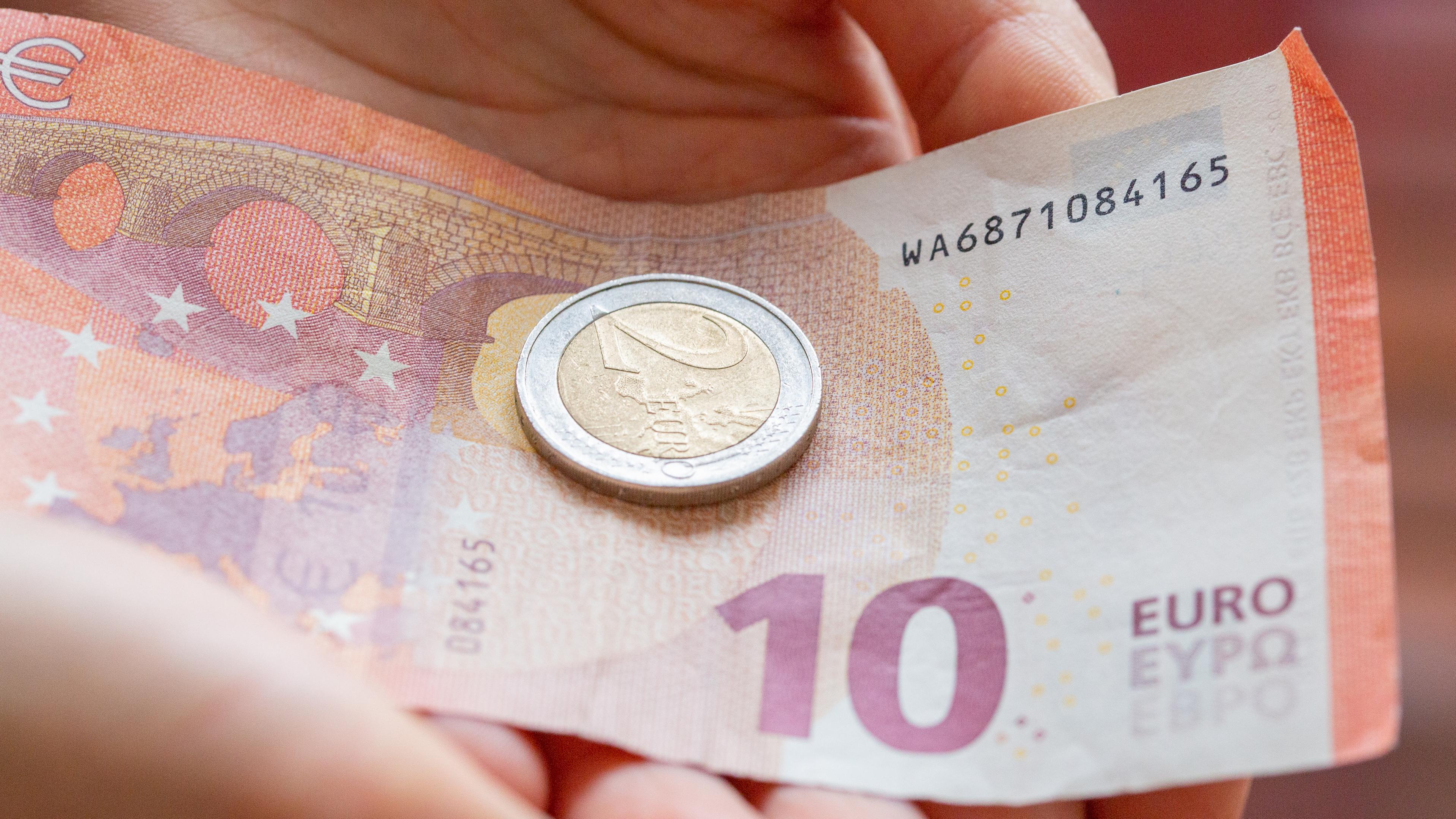 Eine Person hält 12 Euro in der Hand. 