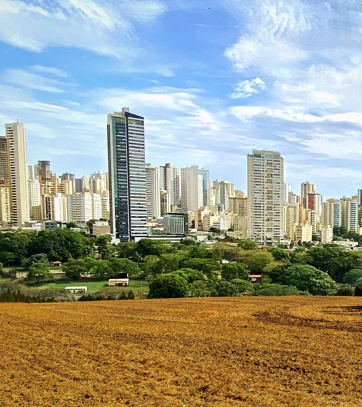 Montage: Vorne ein frisch gepflügtes Feld; im Hintergrund die Skyline einer nahen Großstadt