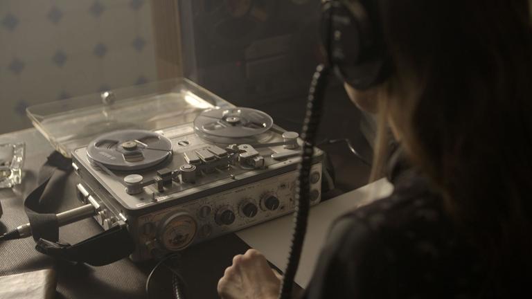 "Geheimes Israel - Der Mossad: Permanente Bedrohung": Eine Person, die man nur von hinten sieht, sitzt mit Kopfhörer auf den Ohren vor einem Abhörgerät (szenische Darstellung).