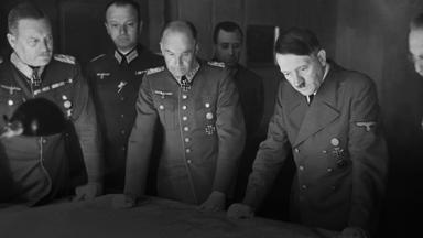 Schwarz-Weiß-Aufnahme von 1941: Militärs der Wehrmacht sowie NS-Diktator Adolf Hitler stehen dicht um einen großen Kartentisch und beraten militärische Operationen.