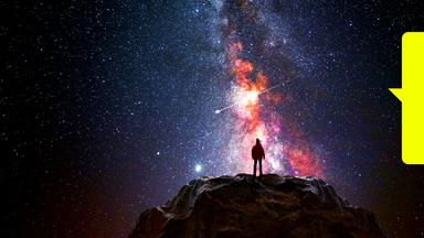 Ein Mann steht auf einem Berggipfel und beobachtet das Universum