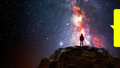 Ein Mann steht auf einem Berggipfel und beobachtet das Universum